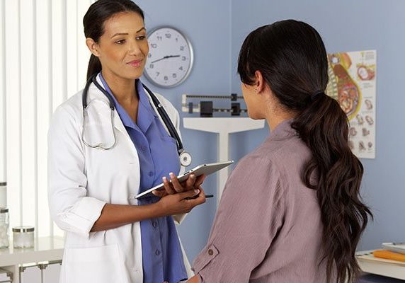 African American gynecologist talking to patient with tablet